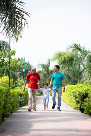 Happy asian family walking and holding hands in the park with nature backgroundの写真素材