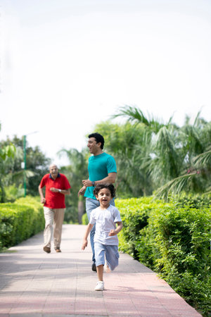 Happy asian family running in the park. Father and son having fun together.の写真素材