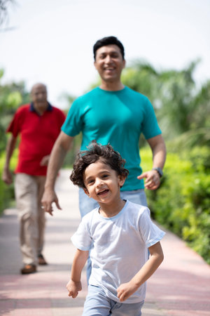 Portrait of a happy little boy running with his father in the parkの写真素材