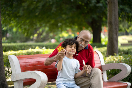 Grandfather and grandson sitting on the bench in the park