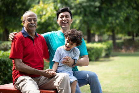 Portrait of happy grandfather and grandson sitting on bench in park at home
