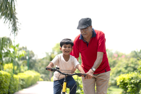 Grandfather teaching grandson to ride bicycle in the park, asianの写真素材