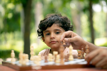 Little boy playing chess in the park. Selective focus on the boy
