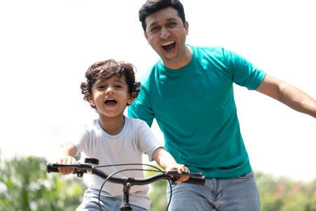 Happy father and son riding bicycle in the park. Concept of friendly family.