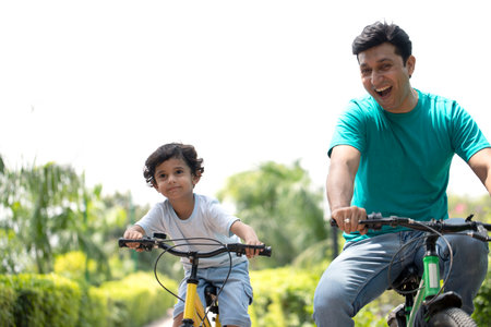 Father and son riding bicycle in the park. Father teaching son to ride bicycle.