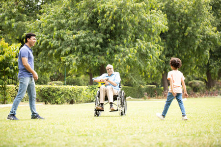 Happy asian family playing in the park with senior man in wheelchair
