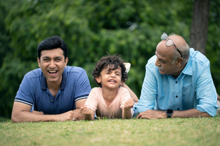 indian family lying on grass and looking at camera in the park