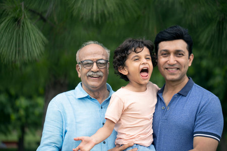 Portrait of Indian grandfather and grandson smiling at camera in the park