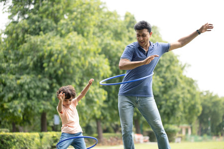 Father and son playing with hula hoop in the park. Concept of healthy family.の写真素材