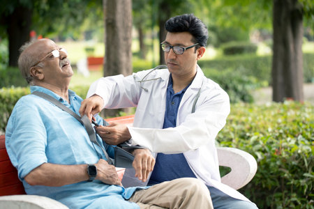 Doctor examining senior patient in the park. Senior healthcare and medical concept.の写真素材