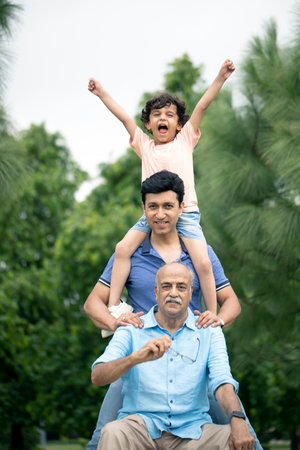 Grandfather, father and daughter having fun together in the park.