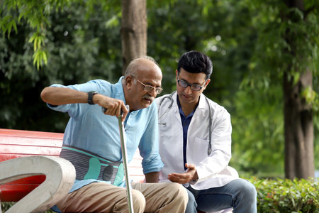 Doctor and senior patient sitting on bench in public park, healthcare and medical conceptの写真素材
