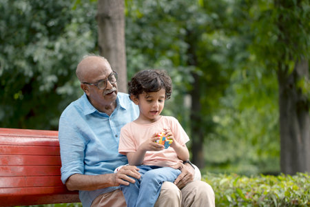 Grandfather and grandson sitting on a bench in the park. Selective focus.の写真素材