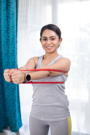 Portrait of smiling sportswoman exercising with resistance band at home