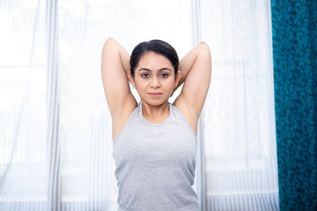 Portrait of beautiful young woman stretching her arms in yoga class at homeの写真素材