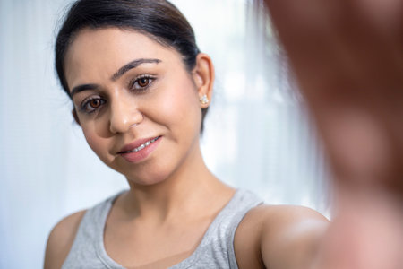 Portrait of smiling woman looking at herself in the mirror at homeの写真素材