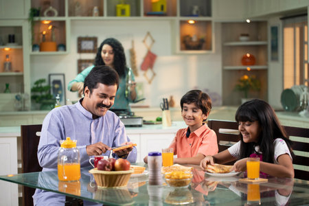 indian family having breakfast together at home, focus on father and daughterの写真素材
