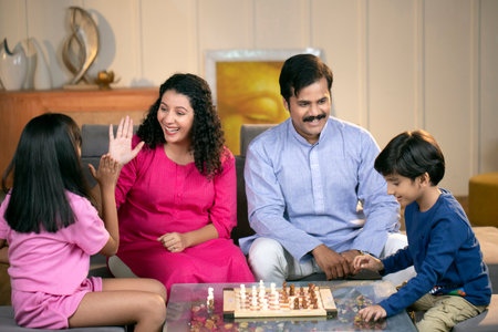 Happy family playing chess together at home. Parents and children spending time together.の写真素材