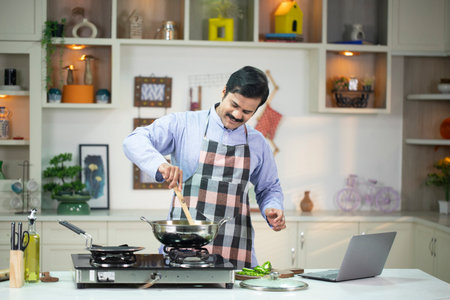 Young man cooking in the kitchen at home. Healthy food concept.の写真素材