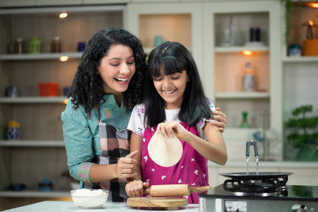 Mother and daughter cooking together in the kitchen at home. Concept of family values.の写真素材
