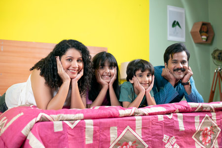 Family sitting on the bed and looking at camera with smile.