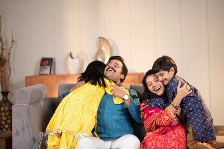 Indian family sitting on sofa in living room and celebrating Holi festivalの写真素材