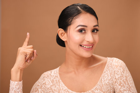 Portrait of a beautiful asian woman smiling and pointing finger upの写真素材