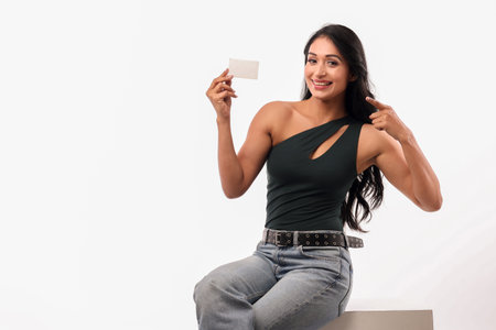 Beautiful young woman holding a blank business card on a white backgroundの写真素材