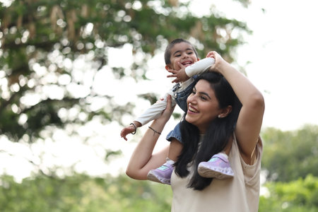 Mother and daughter playing together in the park, happy family concept.