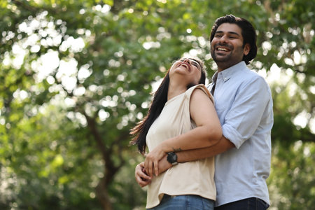 Portrait of young couple embracing each other in park on sunny dayの写真素材