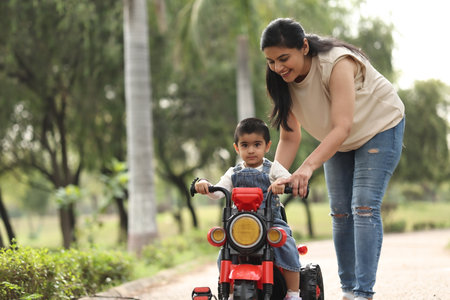 Mother teaching her son to ride a bike in the park.の写真素材