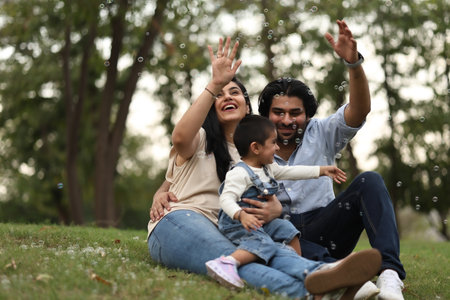 Happy family playing with soap bubbles in the park. Focus on woman