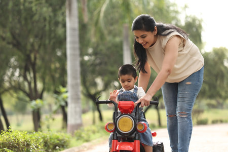 Mother teaching her daughter to drive a scooter in the park.の写真素材