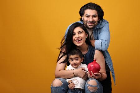 happy indian family with red piggy bank isolated on yellow backgroundの写真素材