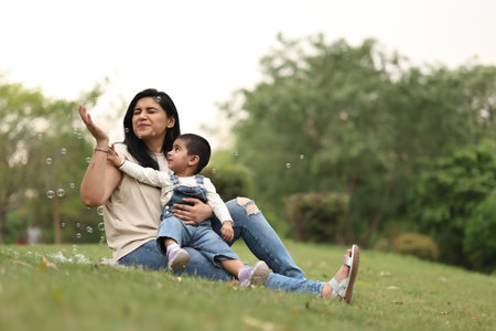 Mother and son playing with soap bubbles in the park. Happy family concept.の写真素材