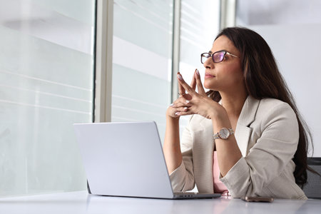 Portrait of young businesswoman sitting at table with laptop in office