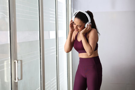 Sporty young woman listening to music with headphones in the gym.