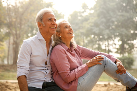Portrait of a happy senior couple sitting in the park at sunset