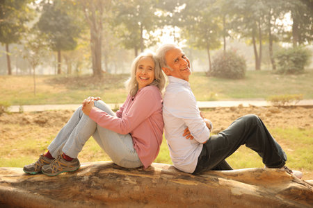 Senior couple sitting on a log in the park on a sunny day