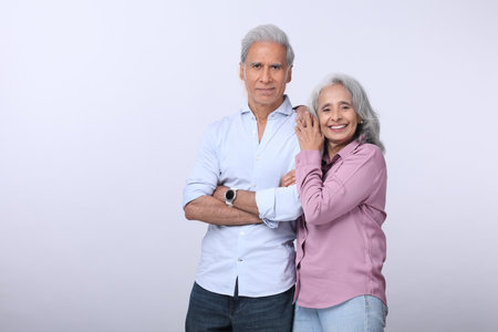 Portrait of a happy senior couple standing with arms crossed against white background