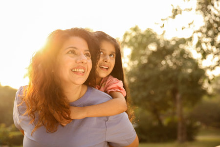 Mother and daughter playing in the park at sunset. Concept of friendly family.