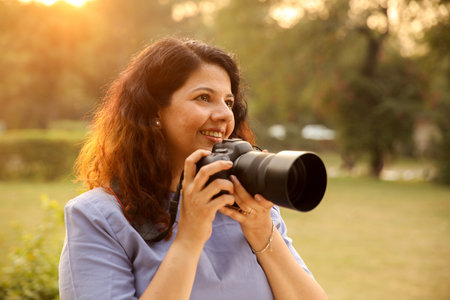 Portrait of a happy mature woman taking photos with camera in the park