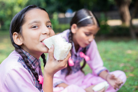 Portrait of smiling schoolgirl eating sandwich in the garden at schoolの写真素材