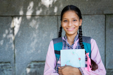 Portrait of smiling schoolgirl holding notebook in school yard on campusの写真素材