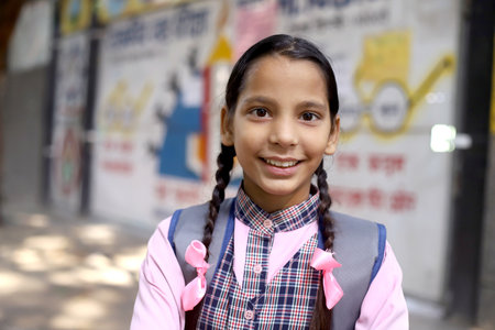 Portrait of a cute little girl in school uniform smiling at cameraの写真素材