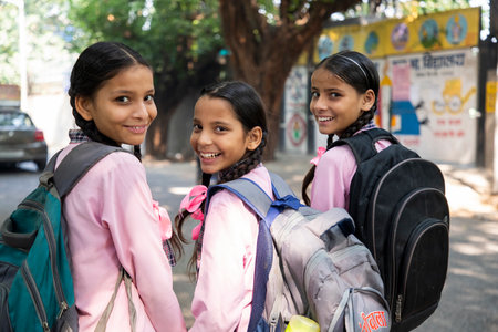 Group of happy schoolgirls with backpacks standing in the street.の写真素材