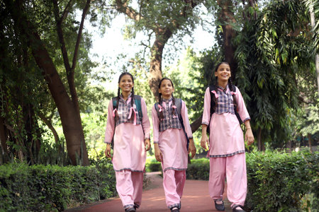 Three girls walking in the park with backpacks and backpacks.の写真素材