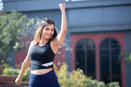 Portrait of happy young woman with arms raised in the street.の写真素材