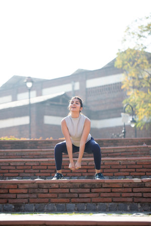 Young woman doing stretching exercises on the steps of an old building.の写真素材