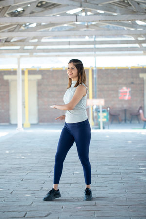 Portrait of a beautiful young woman doing stretching exercise in the city.